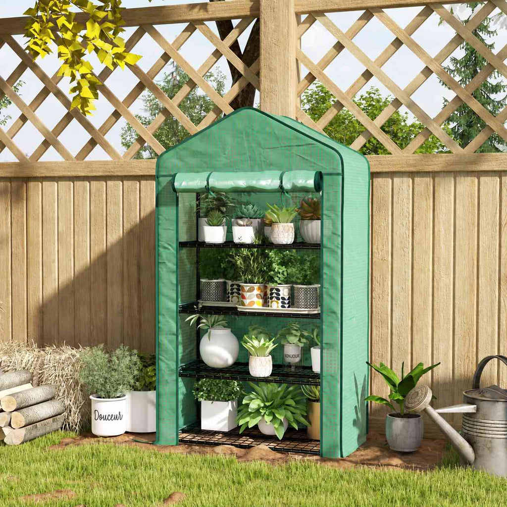 Mini serre verte avec plantes devant un treillage