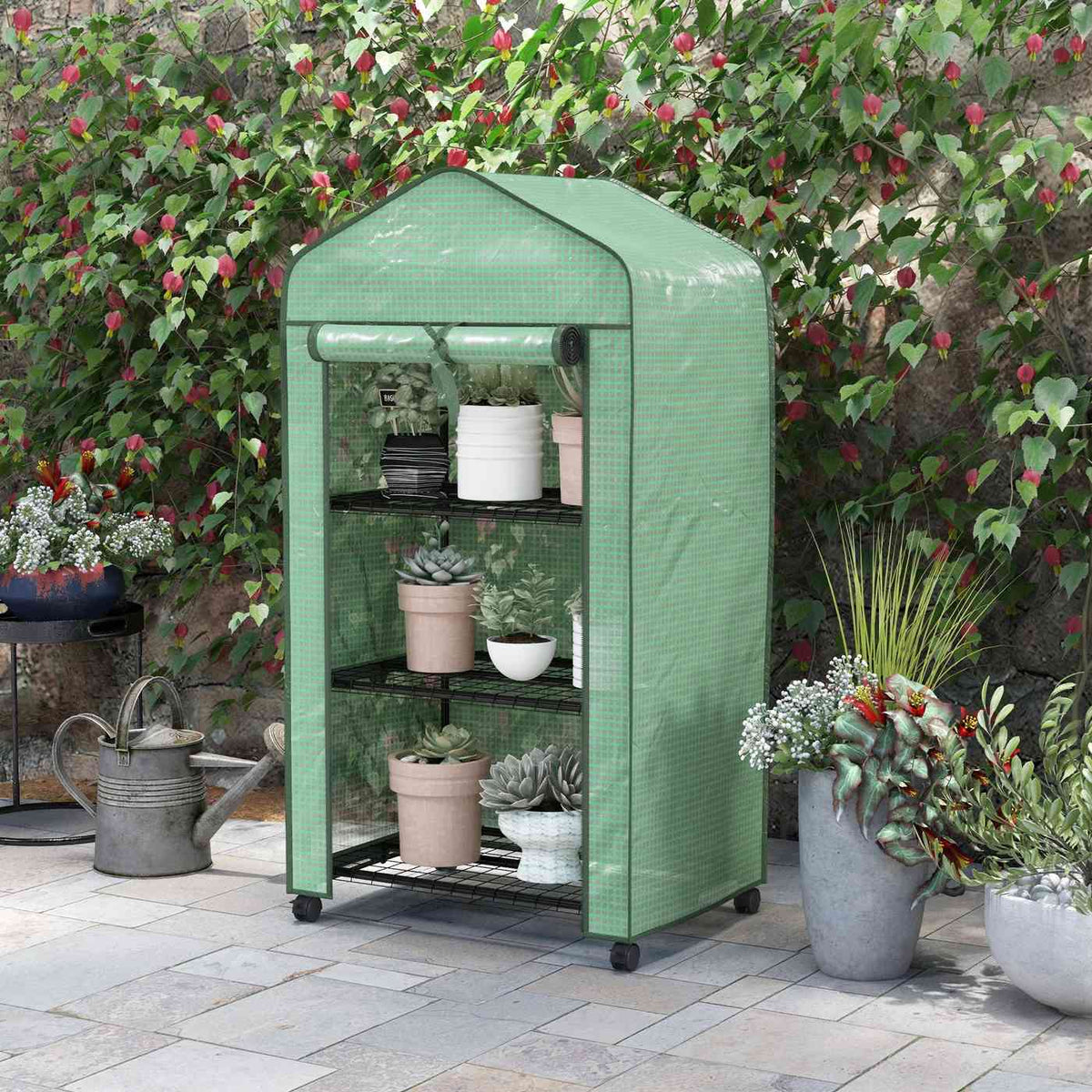 Mini serre verte à roulettes devant des plantes fleuries