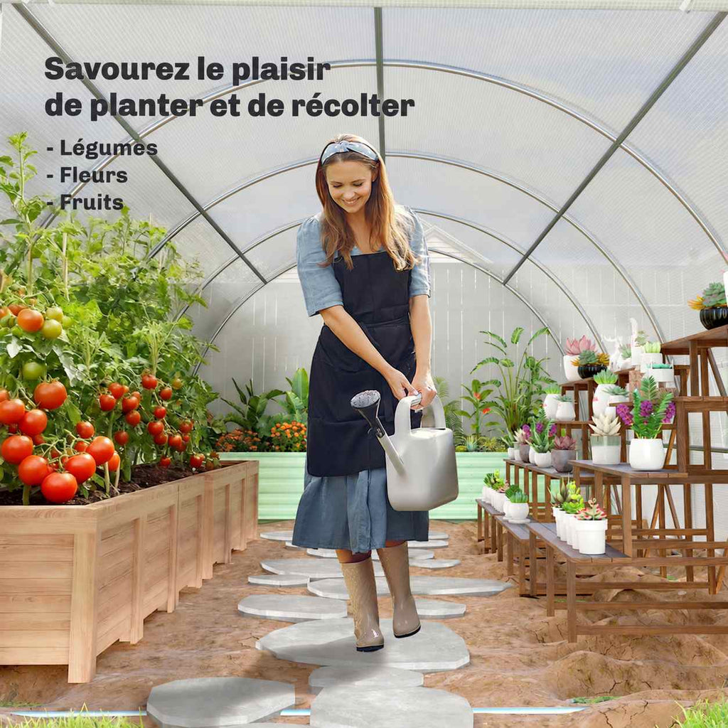 Personne arrosant des plantes à l’intérieur de la serre tunnel blanche