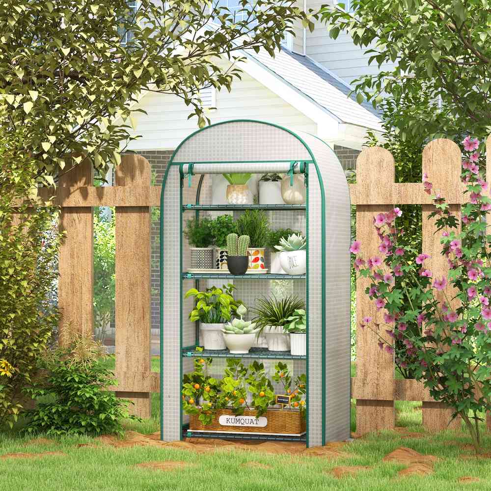 Mini serre blanche avec plantes près d’une clôture