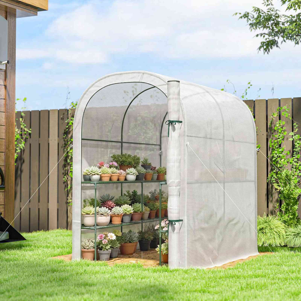 Serre blanche arrondie remplie de plantes en pots dans le jardin