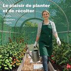 Femme avec arrosoir entre des cultures à l’intérieur d’une serre verte