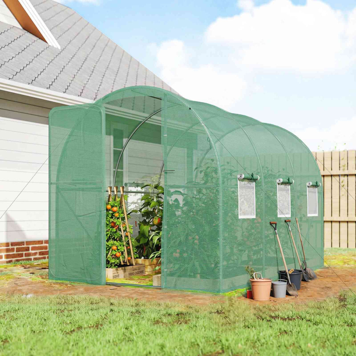 Serre tunnel verte abritant des plantes près d’une maison