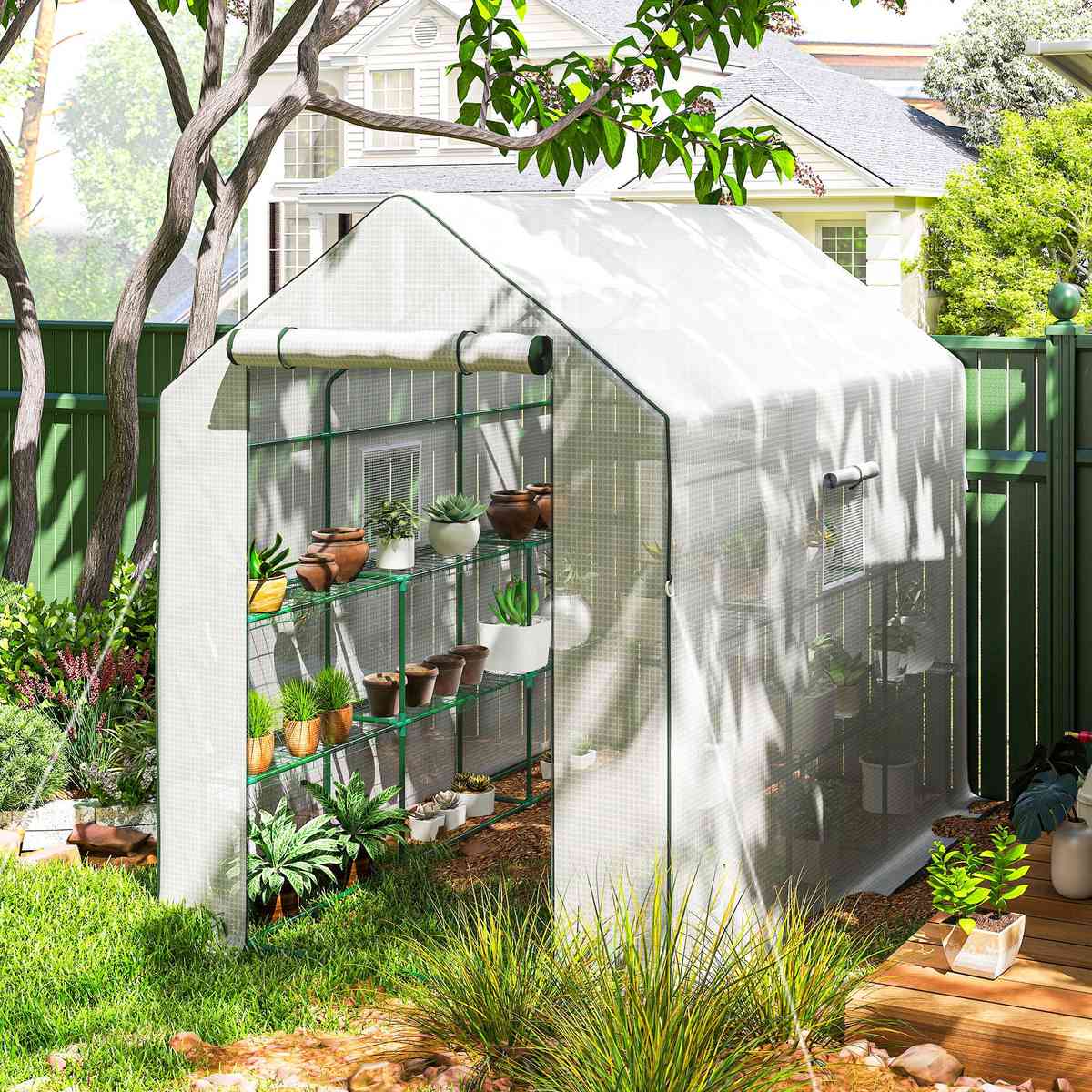 Serre blanche avec plantes sous un arbre au jardin