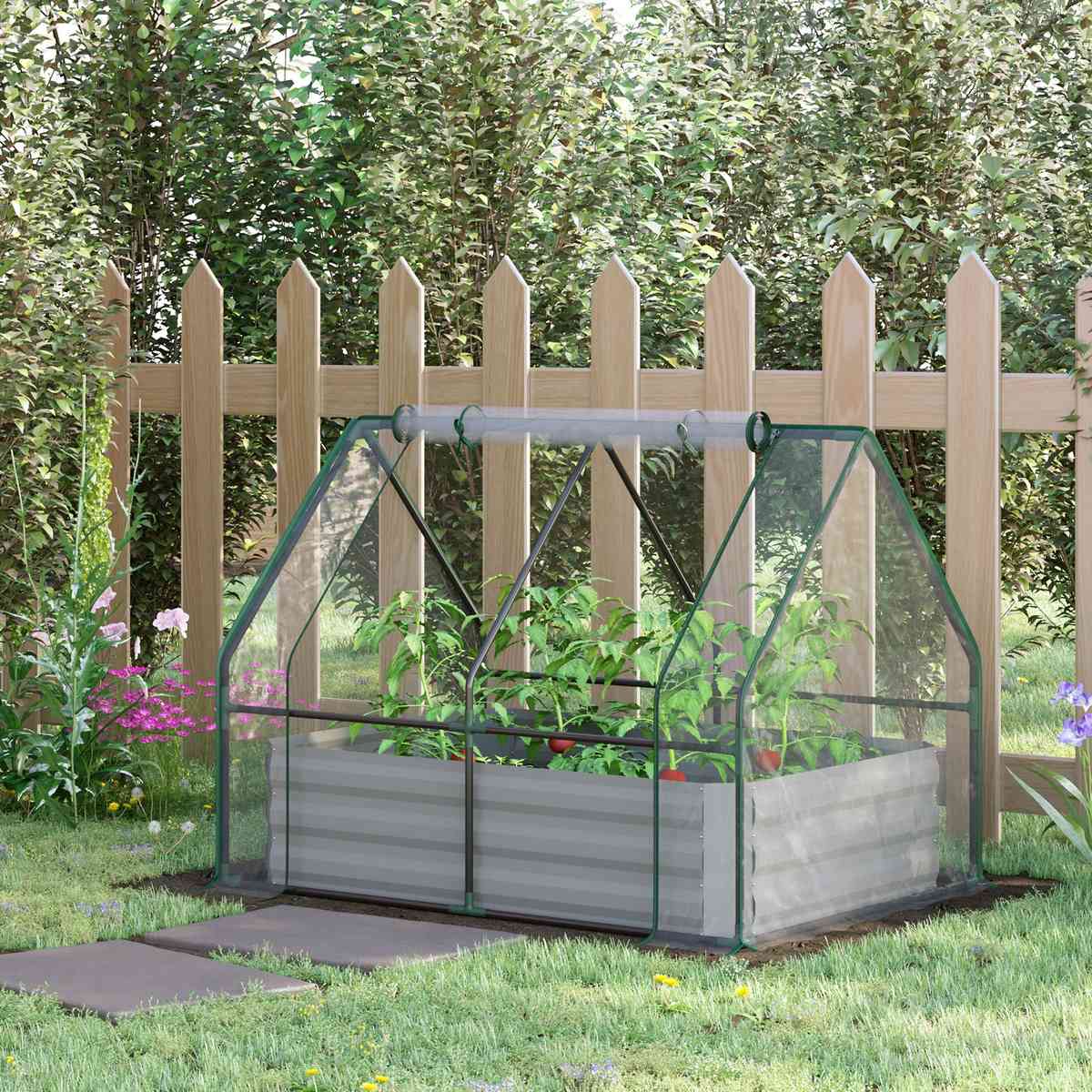 Carré potager serre argenté installé devant une clôture au jardin