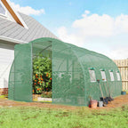 Serre tunnel verte contenant des plantes devant une maison