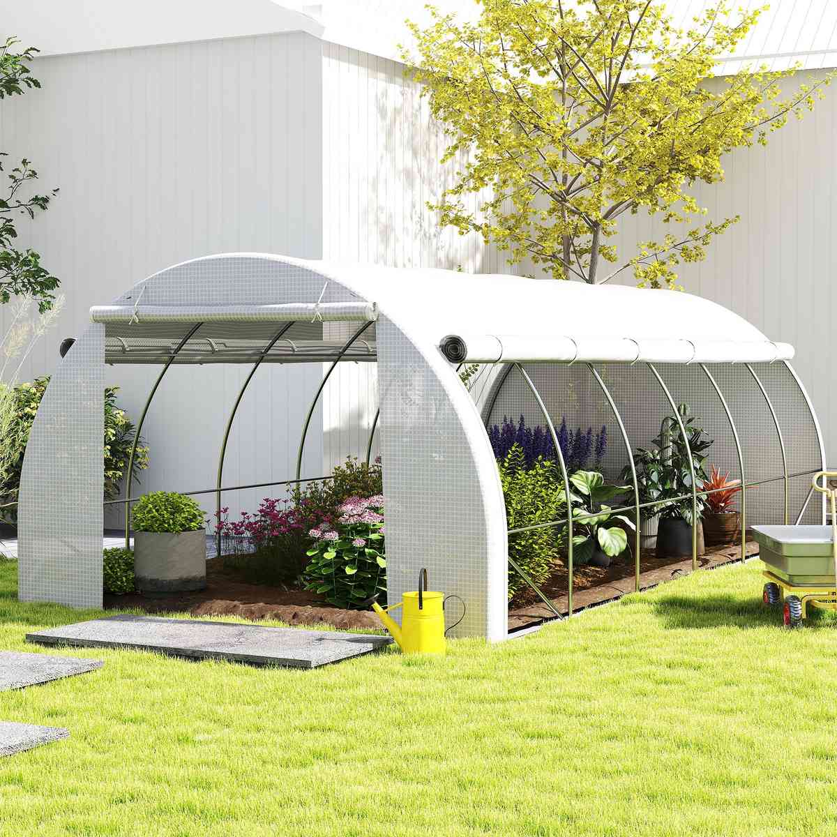 Serre blanche avec côtés relevés et plantes au jardin