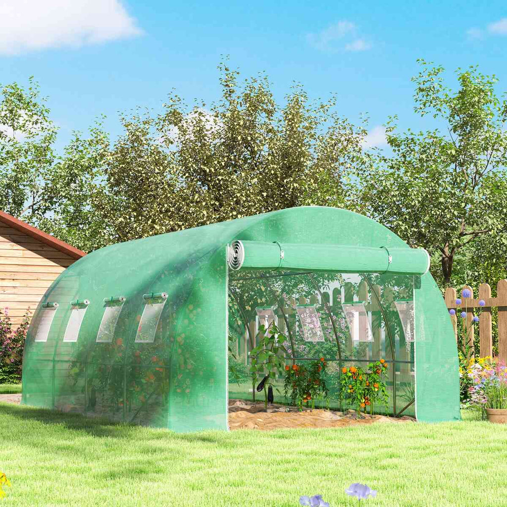 Bâche verte de serre tunnel installée dans un jardin fleuri
