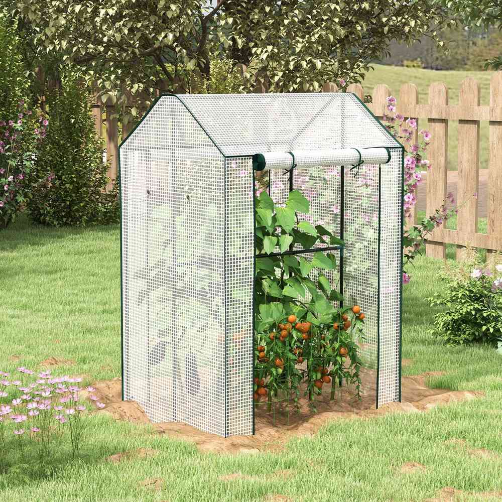Serre blanche avec tomates près d’une clôture