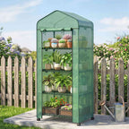 Mini serre verte avec plantes près d’une clôture en bois