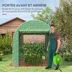 Jardinier avec arrosoir près de la porte de serre verte