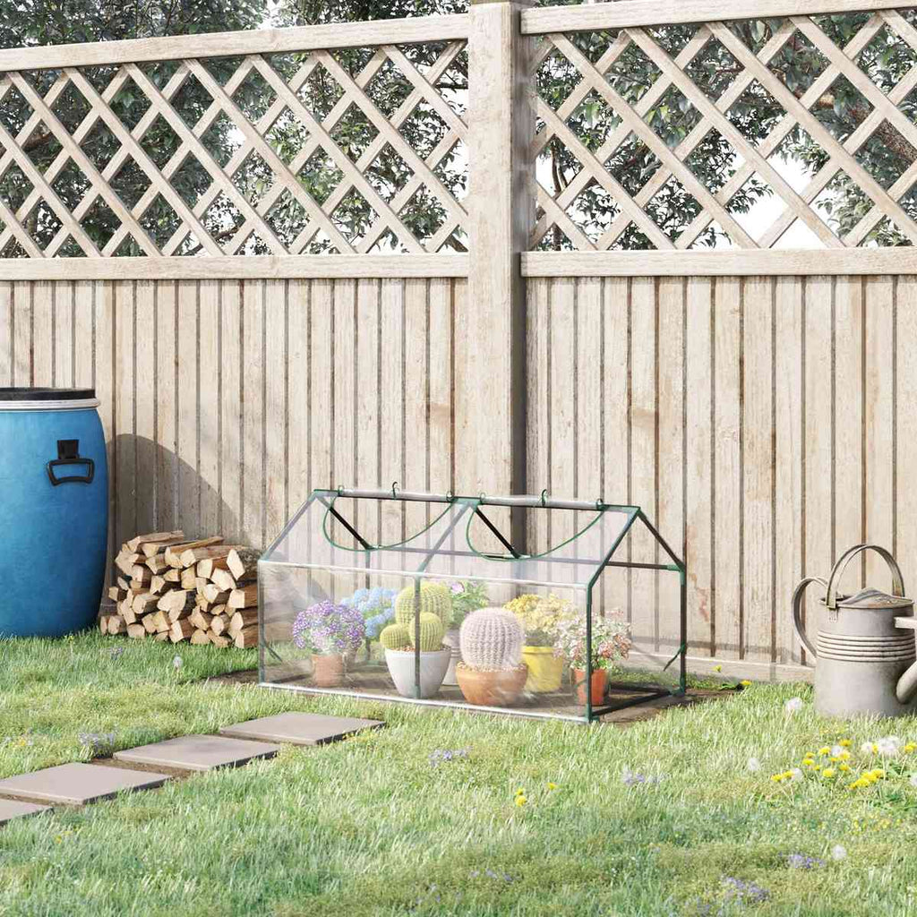 Mini-serre transparente installée devant une clôture au jardin