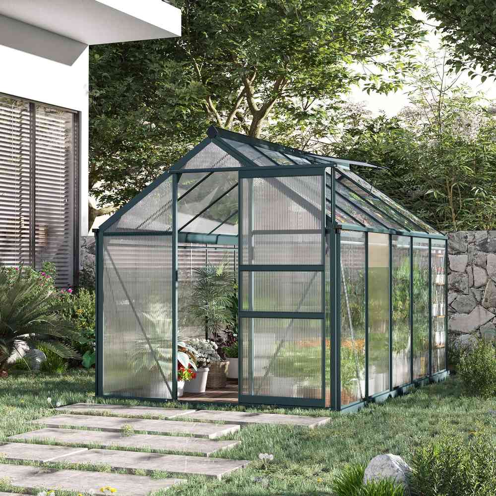 Serre vert foncé installée près d’une maison au jardin