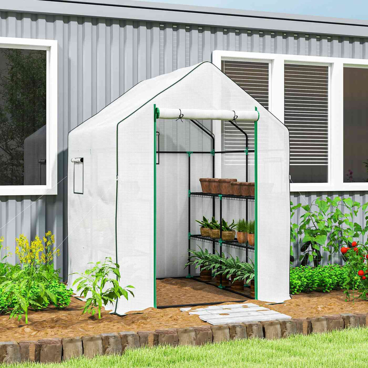Serre blanche avec plantes sur étagères près d’une maison