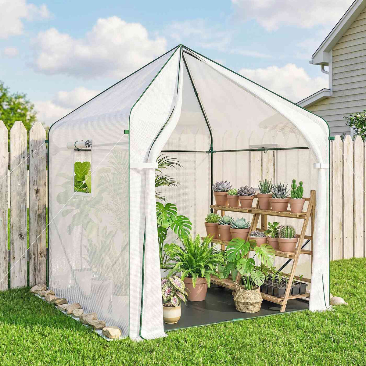 Serre blanche à porte ouverte avec plantes en pots sur une pelouse