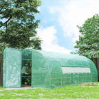 Serre tunnel verte allongée installée dans un jardin arboré