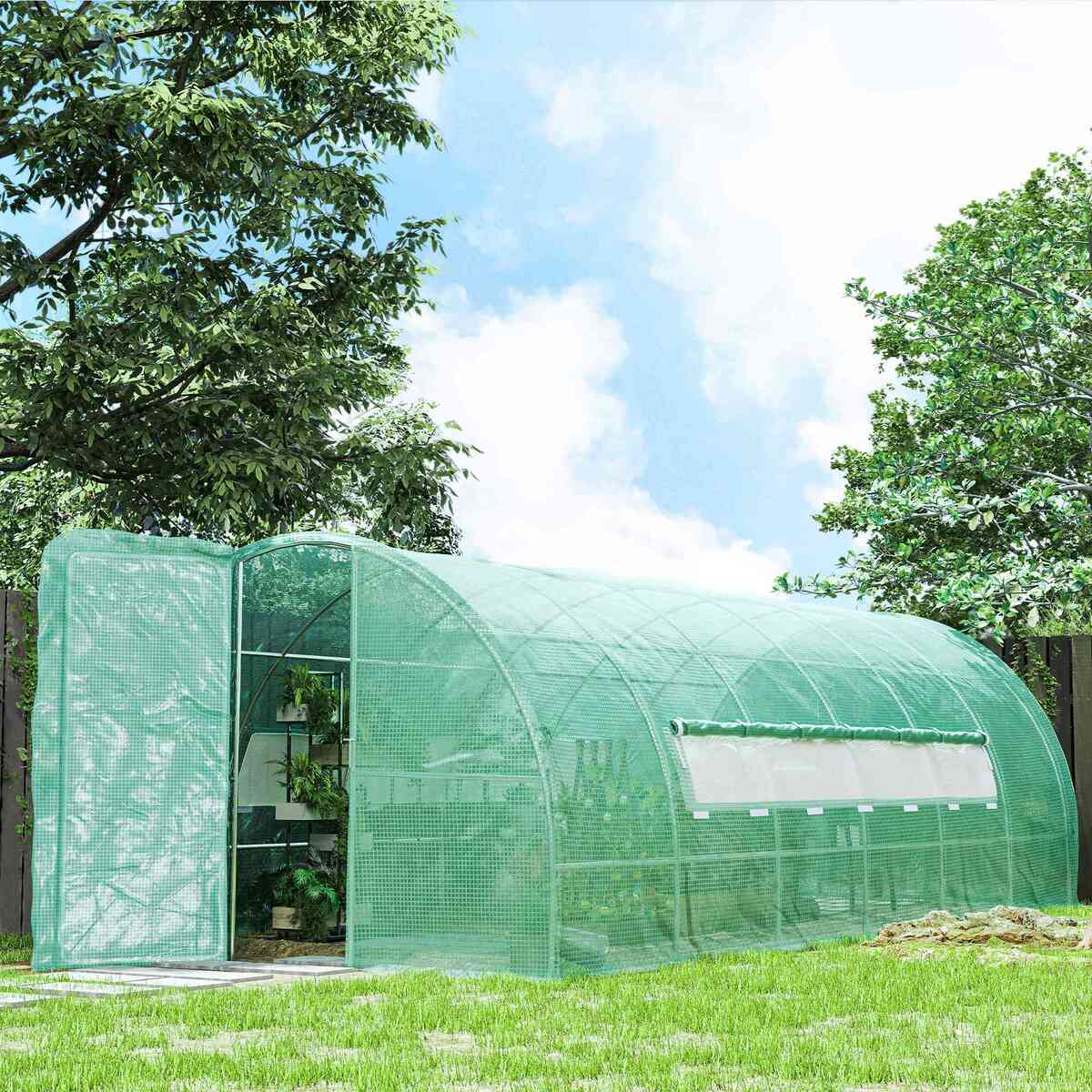 Serre tunnel verte allongée installée dans un jardin arboré