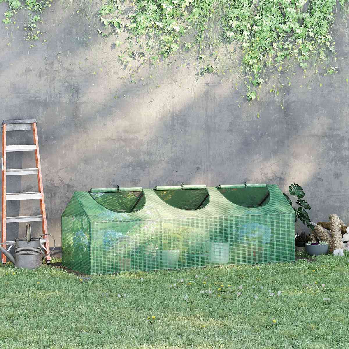 Mini-serre verte garnie de pots contre un mur au jardin