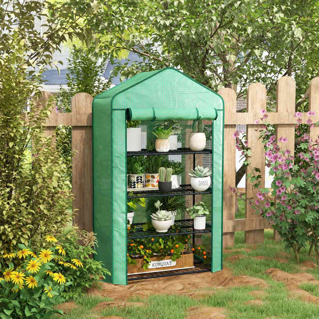 Mini serre verte remplie de plantes près d’une clôture
