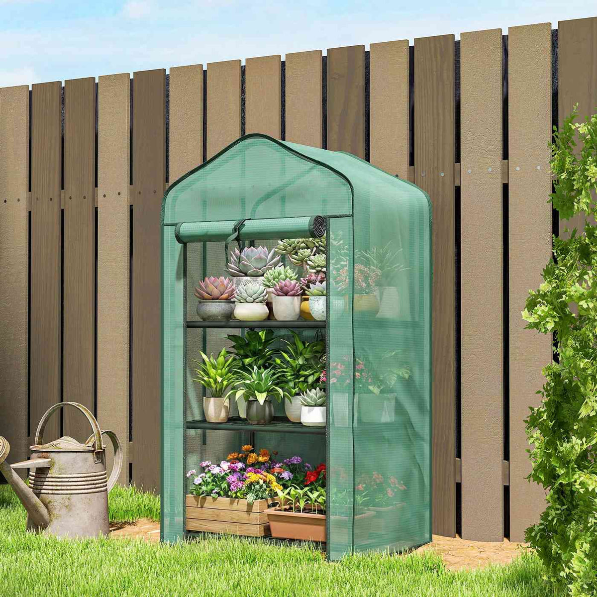 Mini serre verte avec fleurs devant une clôture en bois