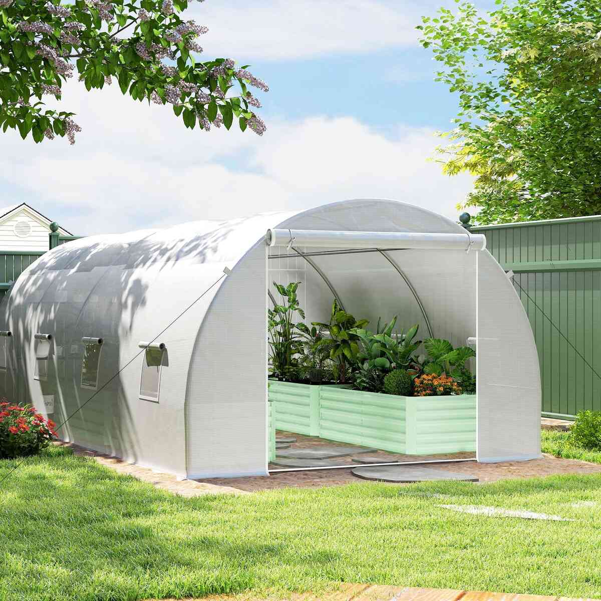 Serre tunnel blanche au jardin avec plantes dans un bac surélevé