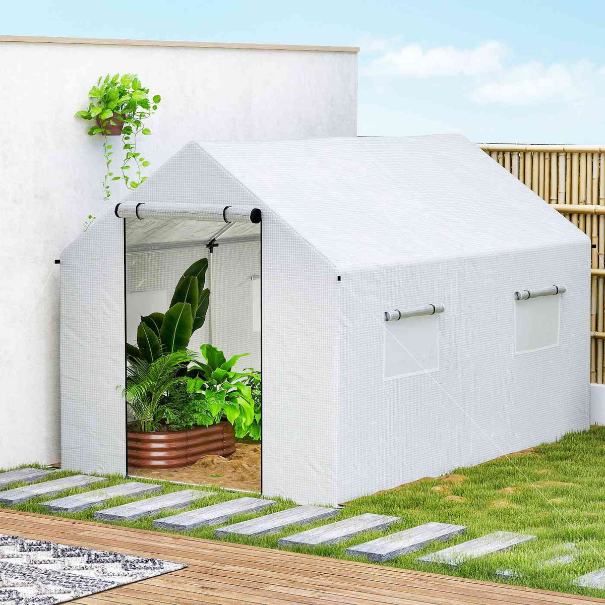 Serre blanche avec plantes près d’un mur et d’une allée