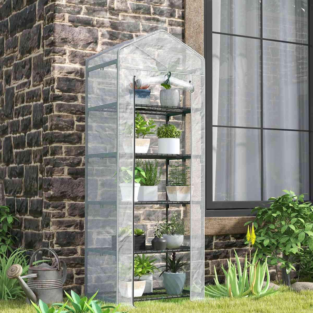 Mini serre transparente avec plantes près d’un mur en pierres