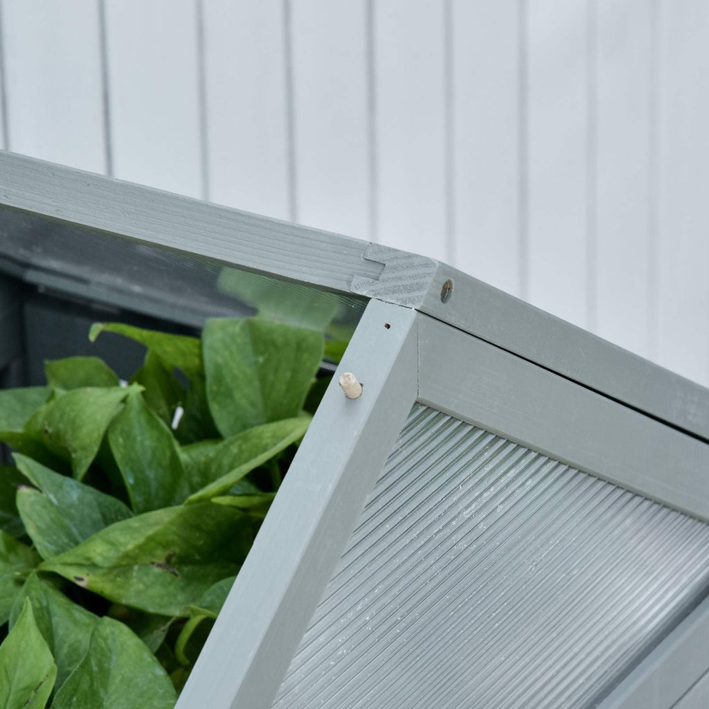 Détail d’une porte ouverte de la serre grise avec plantes à l’intérieur