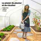 Personne arrosant des plantes dans la serre tunnel blanche