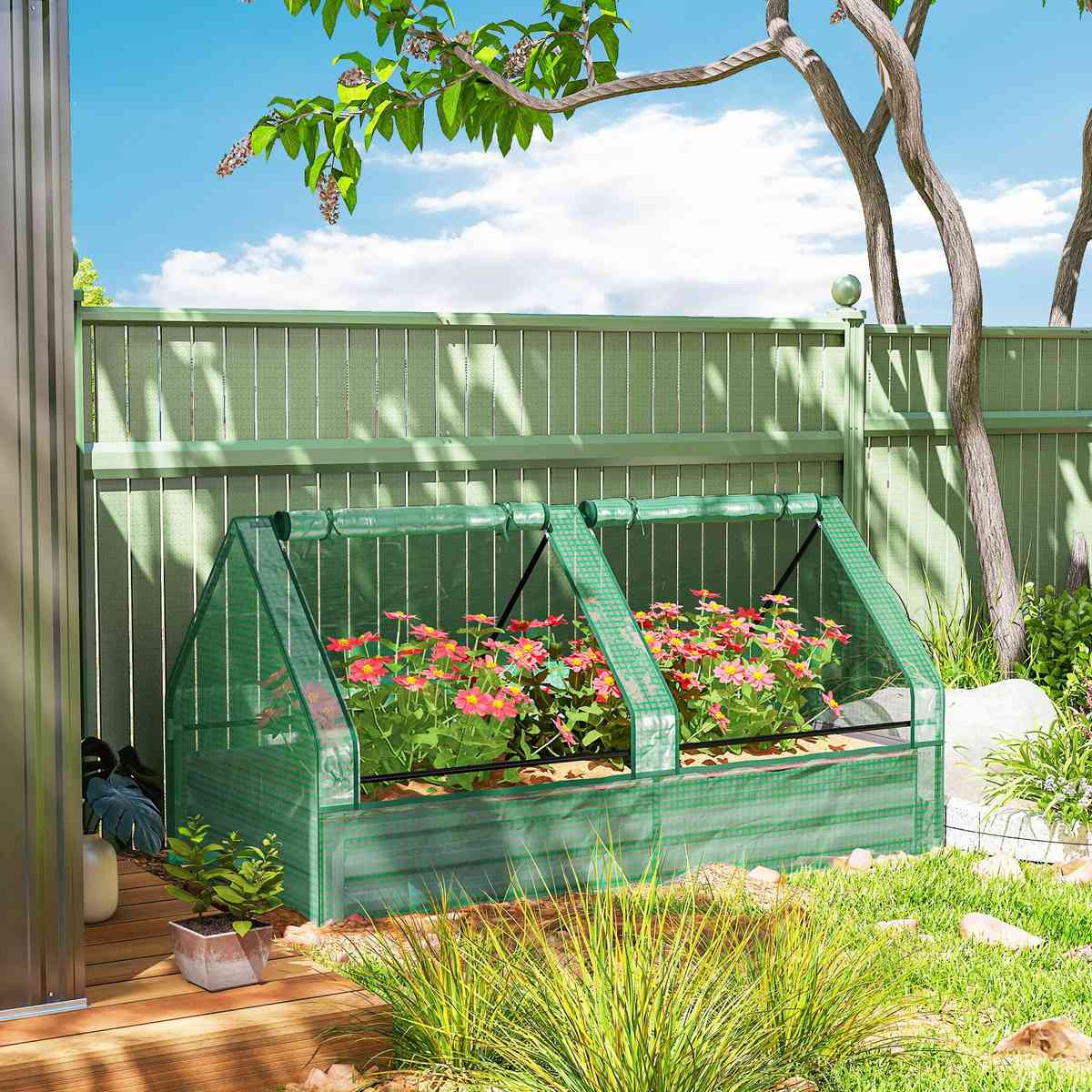 Bac potager couvert vert avec fleurs devant une clôture