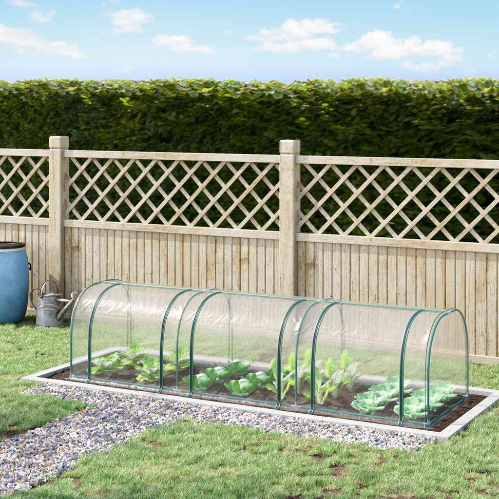 Mini-serre tunnel transparente protégeant des légumes devant une clôture