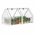 Mini-serre blanche avec deux portes ouvertes et plantes en pots