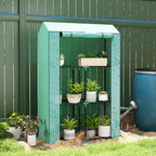 Mini serre verte avec plantes en pots devant une clôture