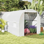Serre tunnel blanche garnie de plantes fleuries au jardin