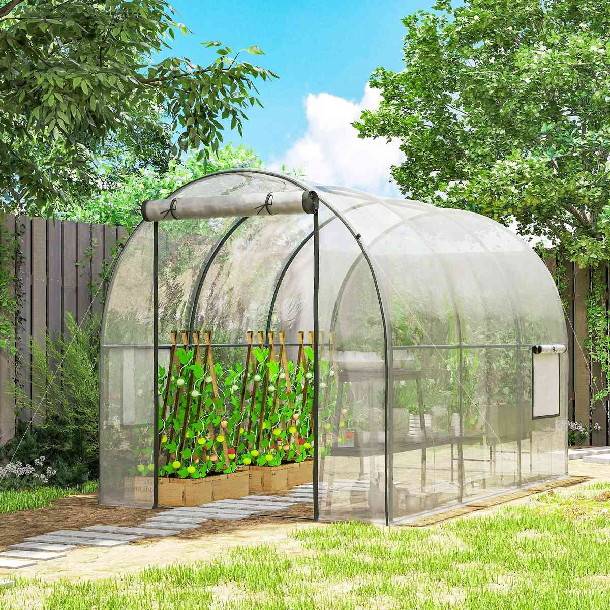 Serre tunnel transparente avec cultures près d’une clôture