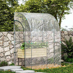 Serre adossée transparente contenant un bac potager contre un mur en pierres