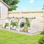 Mini serre tunnel blanche avec plantes en pots près d’une clôture