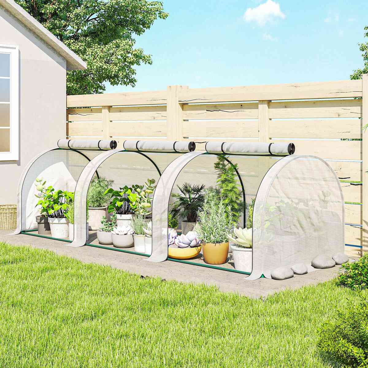 Mini serre tunnel blanche avec plantes en pots près d’une clôture