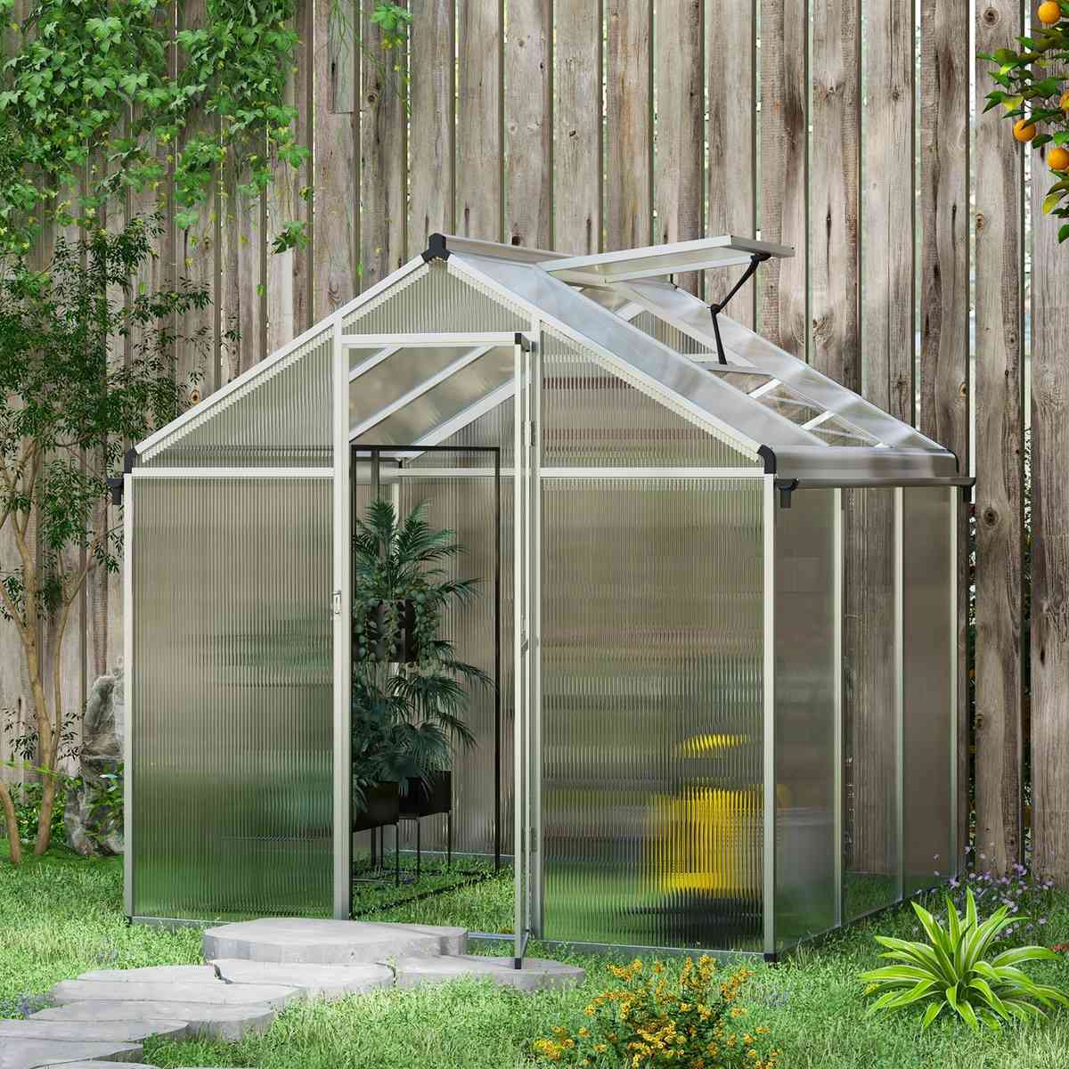 Serre en polycarbonate installée près d’une clôture en bois