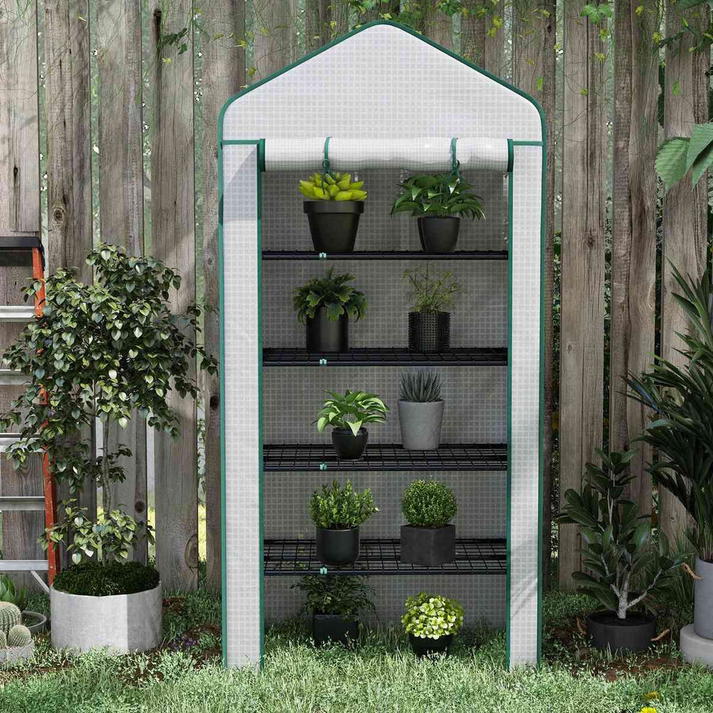 Serre blanche avec plantes devant une clôture en bois