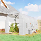 Serre tunnel blanche près d’une maison avec tomates à l’intérieur