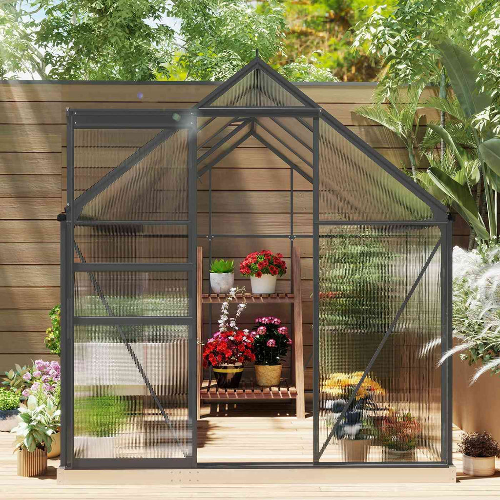 Vue de face de la serre grise avec porte ouverte et fleurs à l’intérieur