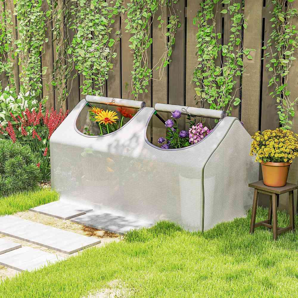 Mini-serre blanche au jardin devant une clôture en bois
