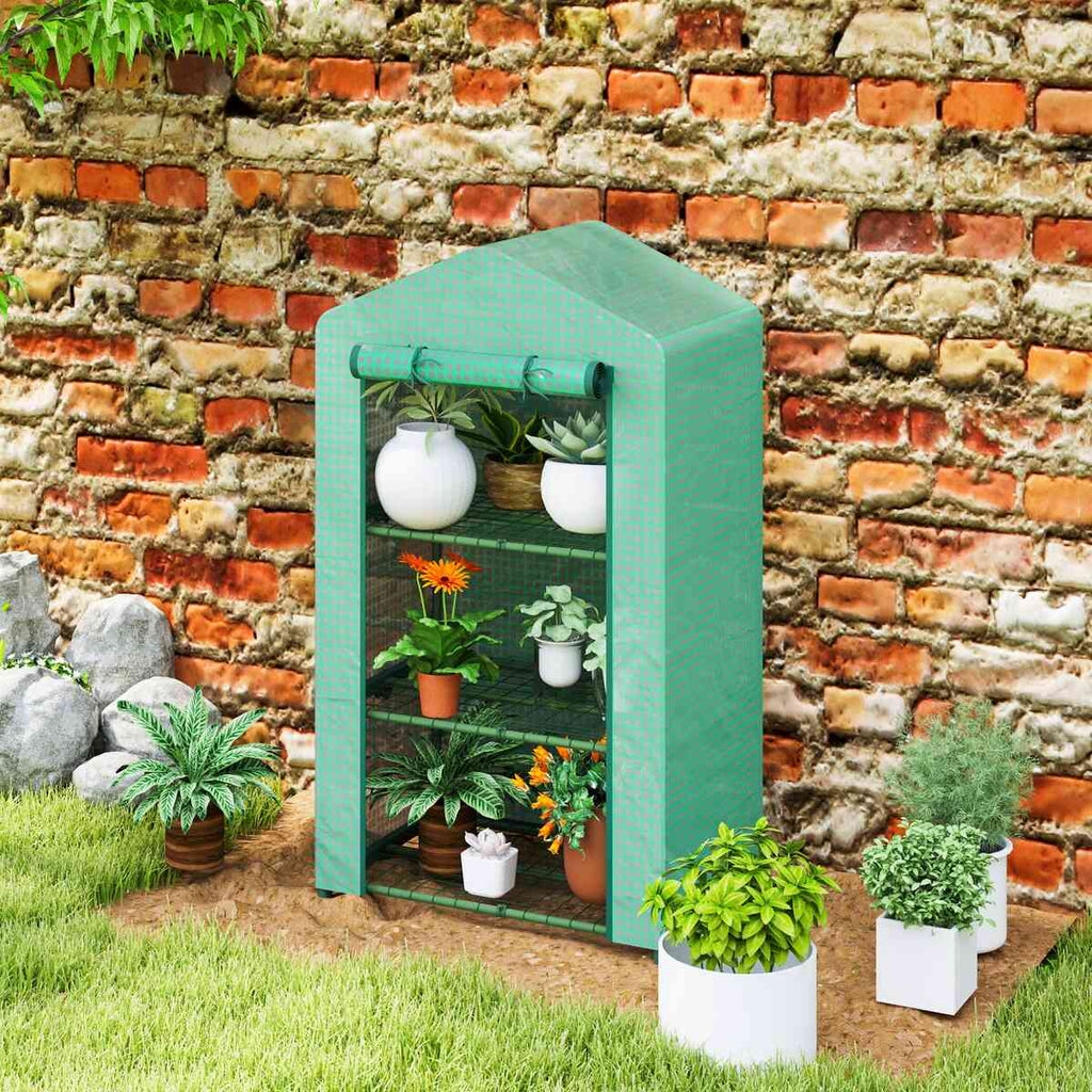 Mini serre verte remplie de plantes contre un mur en briques