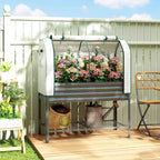 Bac potager avec serre et fleurs roses sur une terrasse en bois