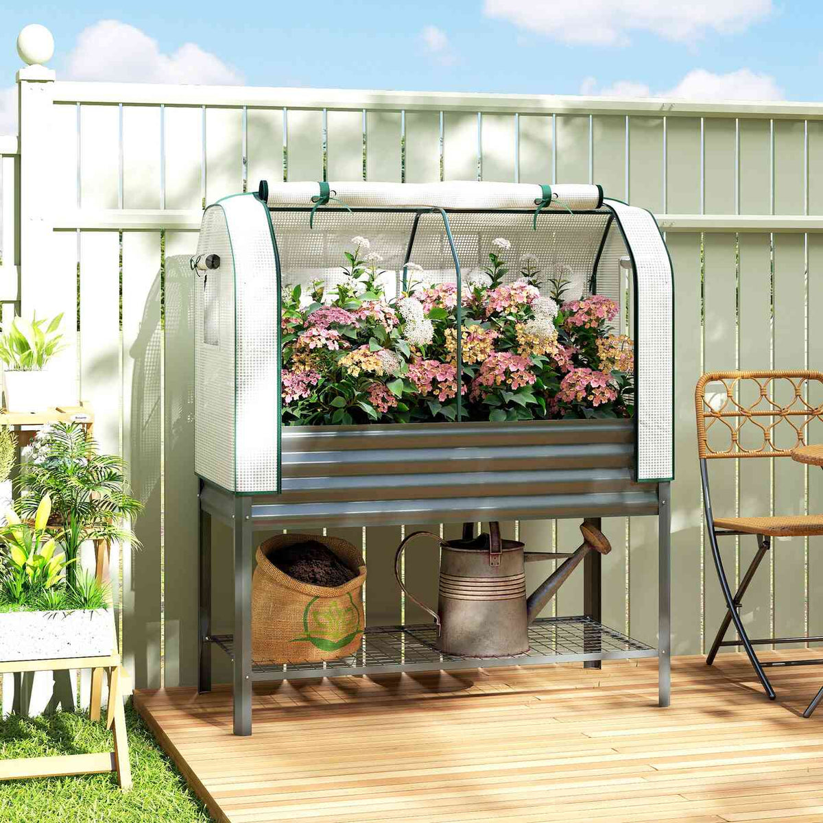 Bac potager avec serre et fleurs roses sur une terrasse en bois