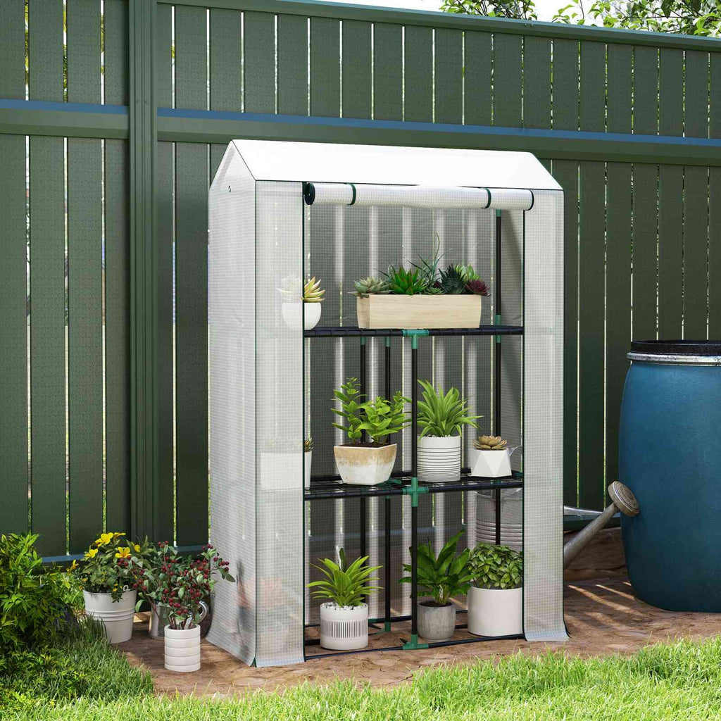 Mini serre blanche avec plantes en pots devant une clôture