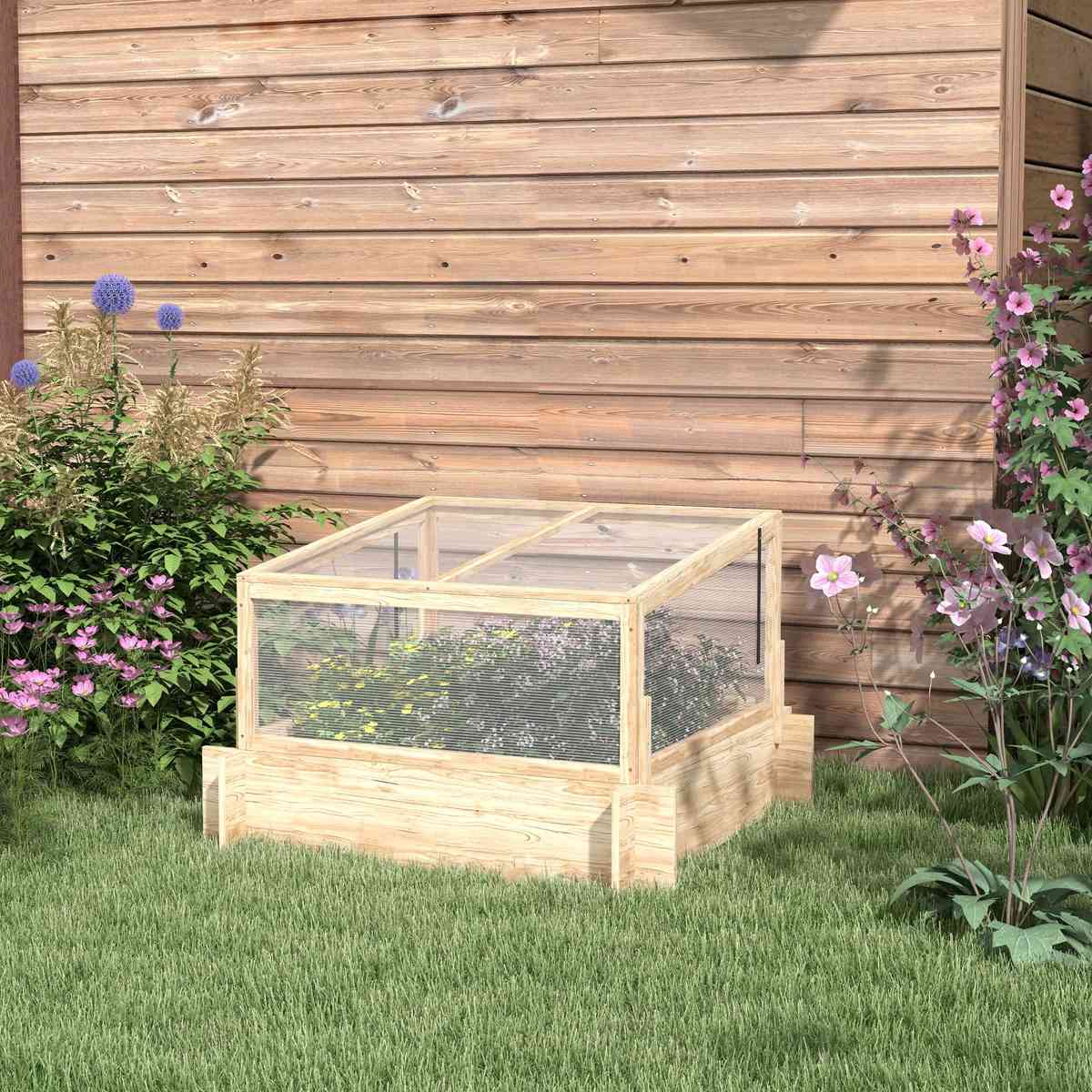 Carré potager en bois avec serre installé près d’un mur
