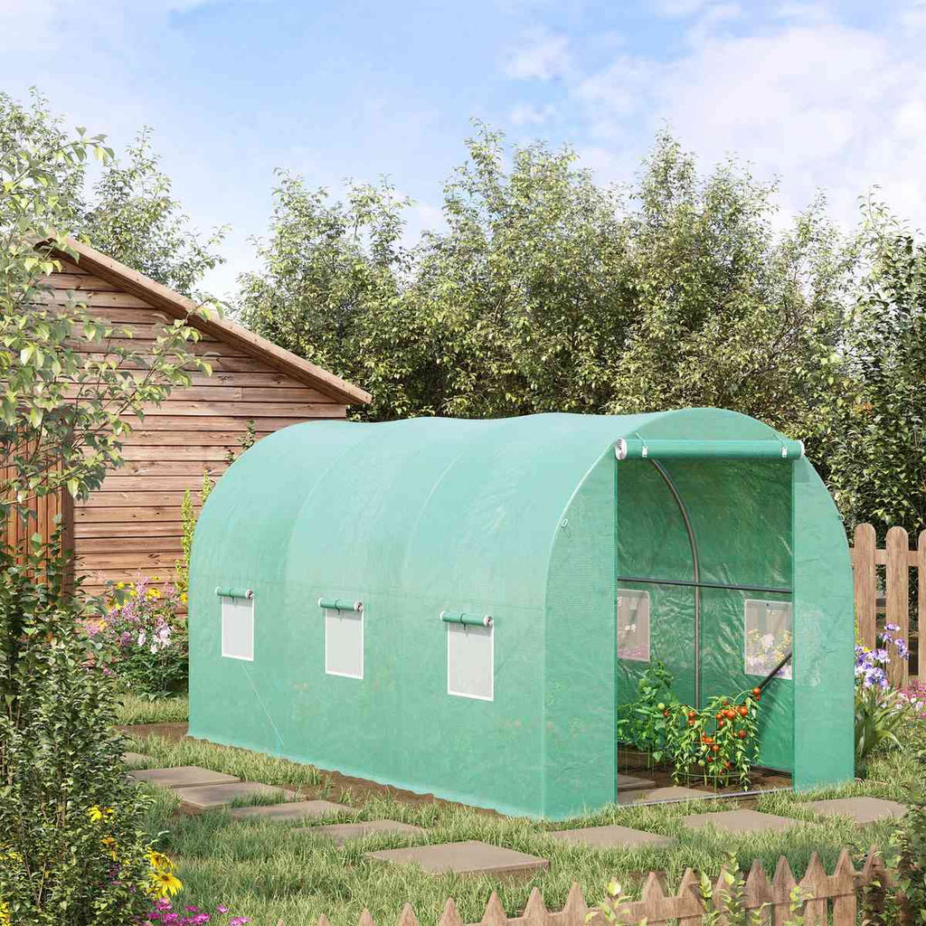 Serre tunnel verte au jardin avec cultures devant l’entrée