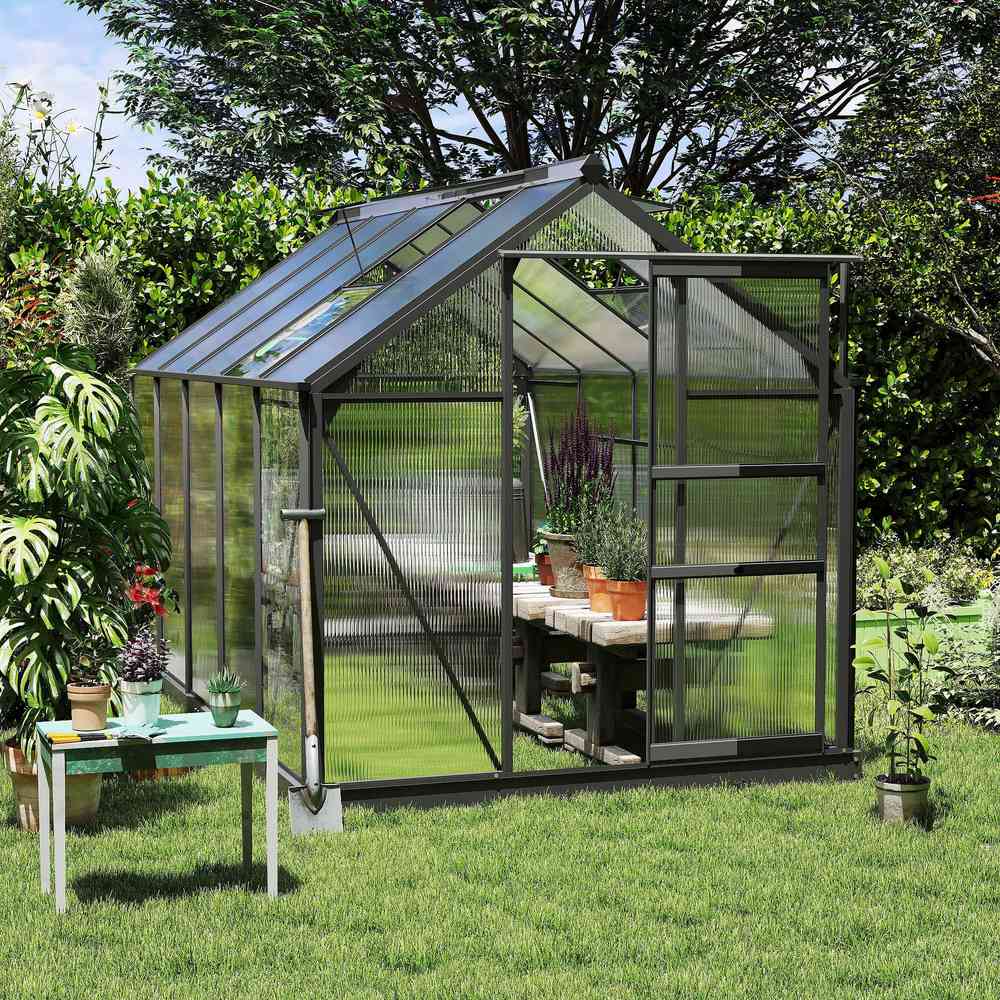 Serre gris foncé au jardin avec une table et des plantes à l’intérieur